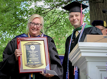 Dr. Jean (Scheller) Sampson ‘83, left, receives the 2022 William Norman Grandy Faculty Award from Ryan Furniss ’00, Alumni Association president, during commencement.